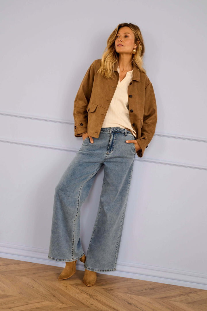 Femme portant une Veste décontractée Cala en suédé avec jeans évasés, tenue de mi-saison élégante et moderne, style utilitaire chic.