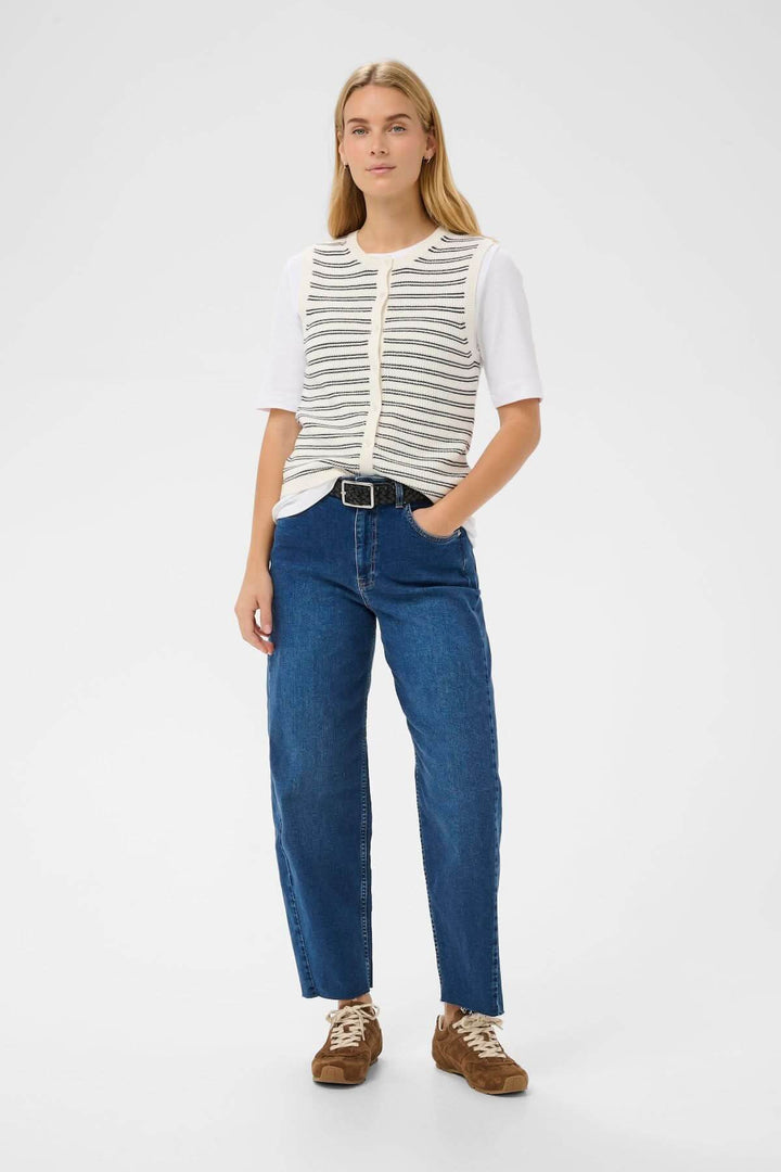 Femme portant la Veste de tricot Gemma, coupe droite, sans manches, allure minimaliste, sur un t-shirt blanc avec un jean bleu.