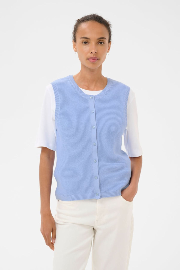Veste de tricot Gemma portée par un modèle, coupe droite sans manches, élégante et minimaliste avec patte de boutonnage classique.