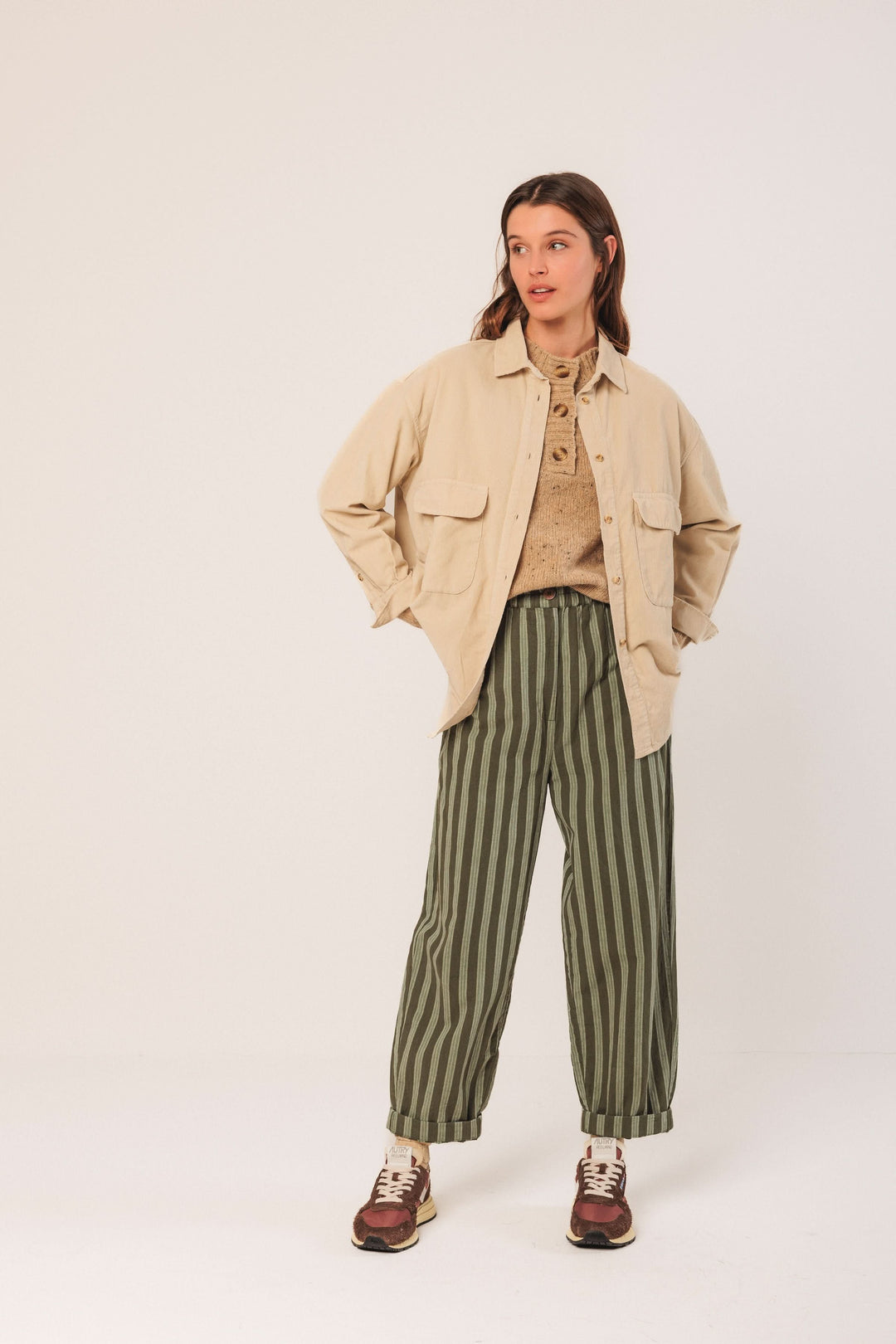 Femme portant une veste en velours côtelé beige avec un pantalon à rayures vertes, style décontracté et tendance.