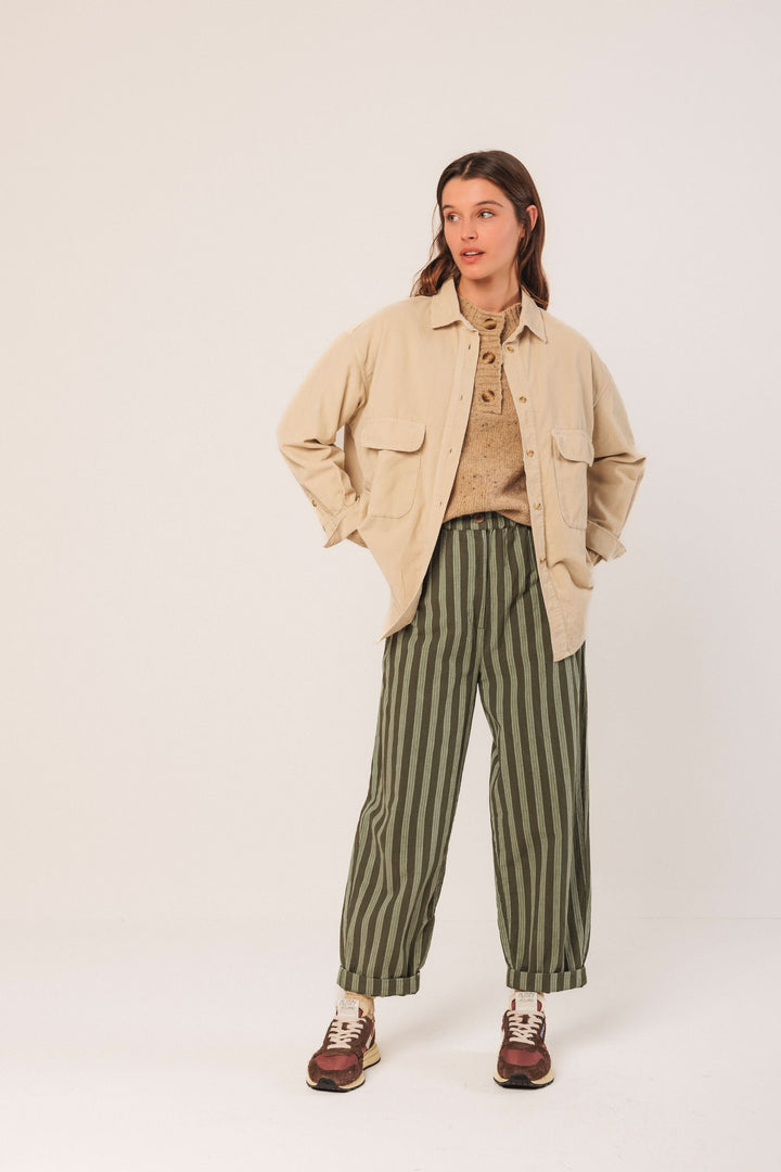 Femme portant une veste en velours côtelé beige avec un pantalon à rayures vertes, style décontracté et tendance.