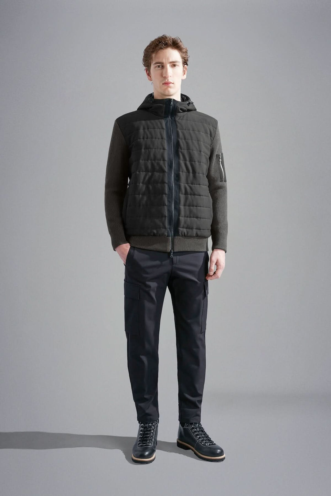 Homme portant une veste imperméable à capuchon, matelassée à l'avant et confortable, avec pantalon noir.