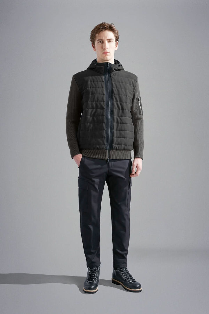 Homme portant une veste imperméable à capuchon, matelassée à l'avant et confortable, avec pantalon noir.