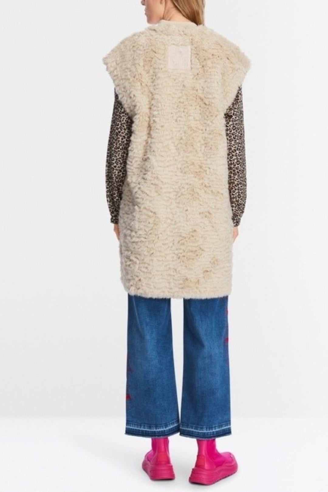 Veste longue en fourrure bouclée, ample, avec épaules recoupées, portée par un mannequin, style décontracté.