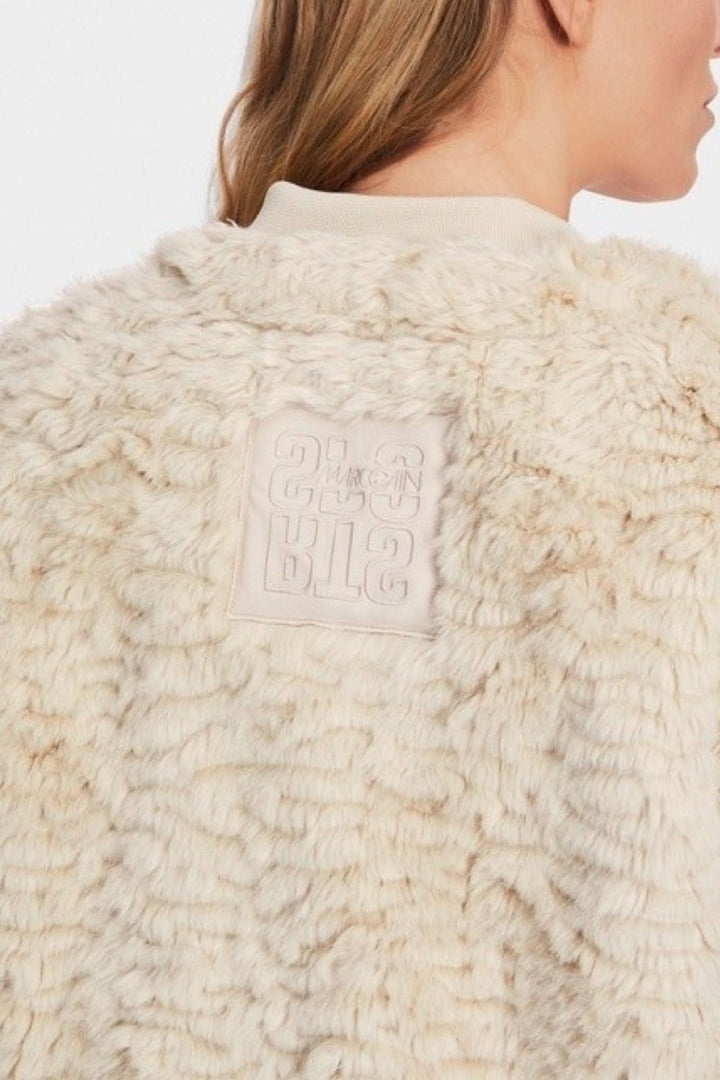 Veste longue en fourrure bouclée beige avec détails en tissu sur le col et logo sur l'arrière.