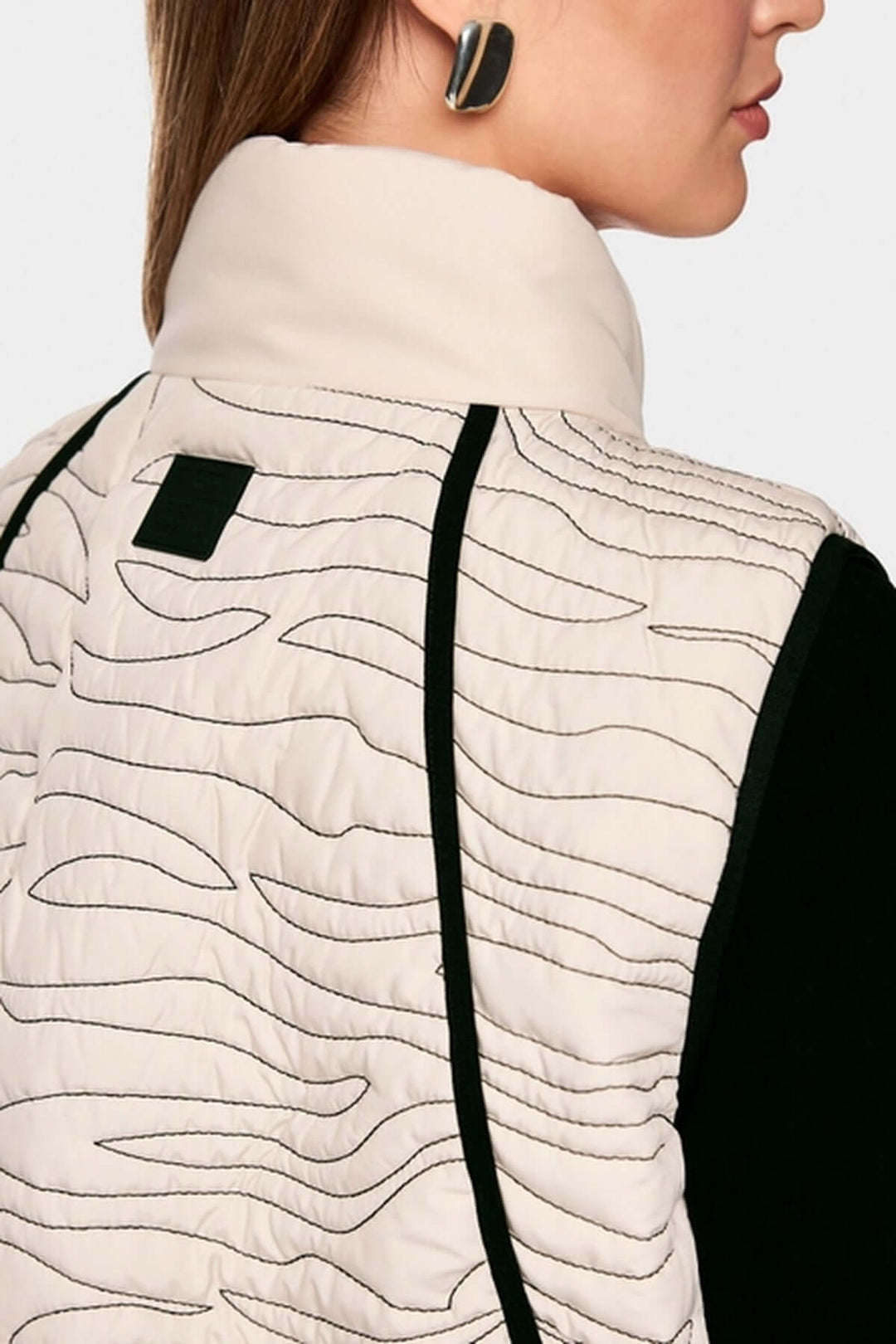 Veste matelassée avec surpiqûres ondulées et col montant pour chaleur, en blanc et noir, idéale pour un look moderne et chaud.