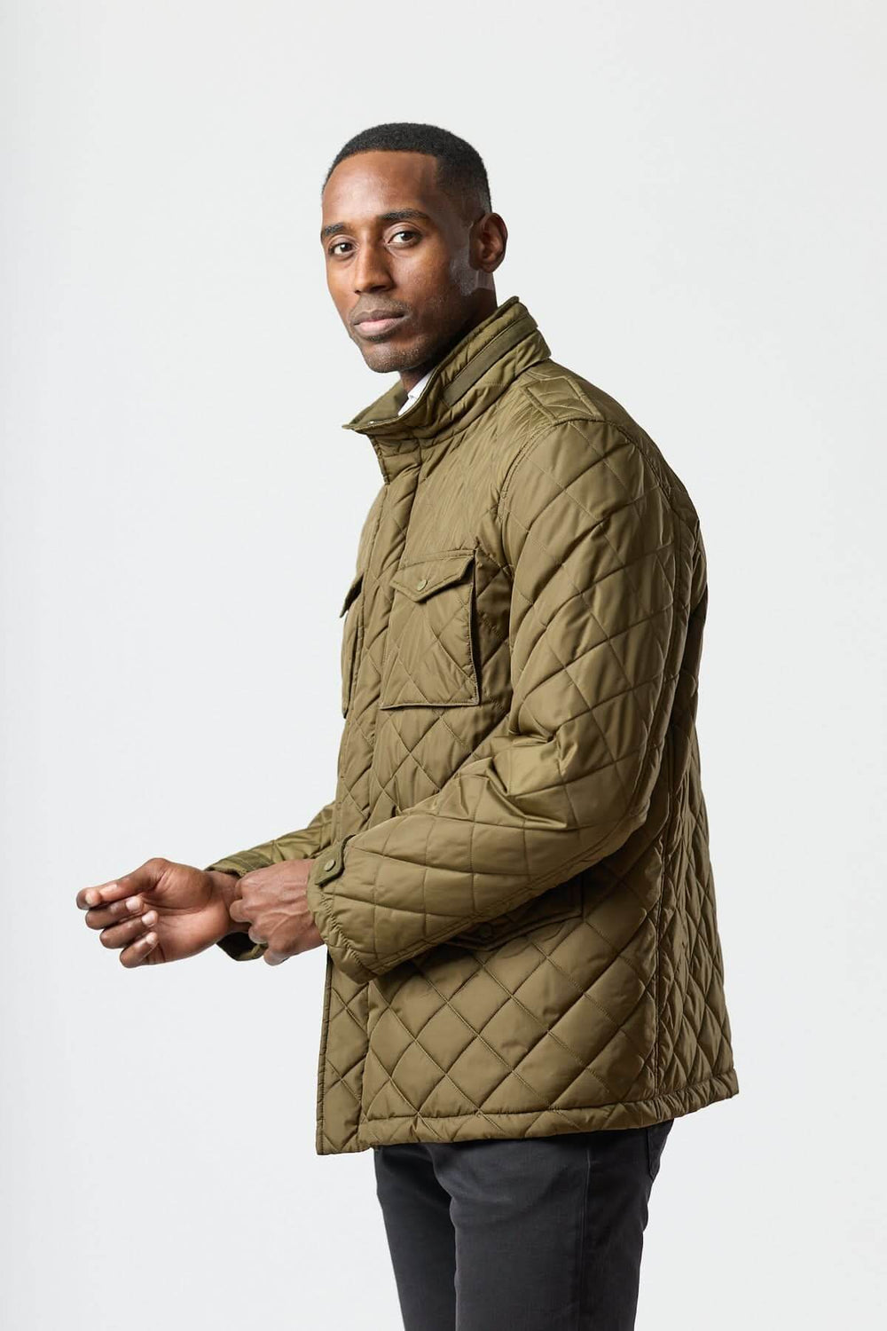 Homme portant une veste matelassée à capuche escamotable, col montant, couleur kaki, look utilitaire, idéale pour mi-saison.