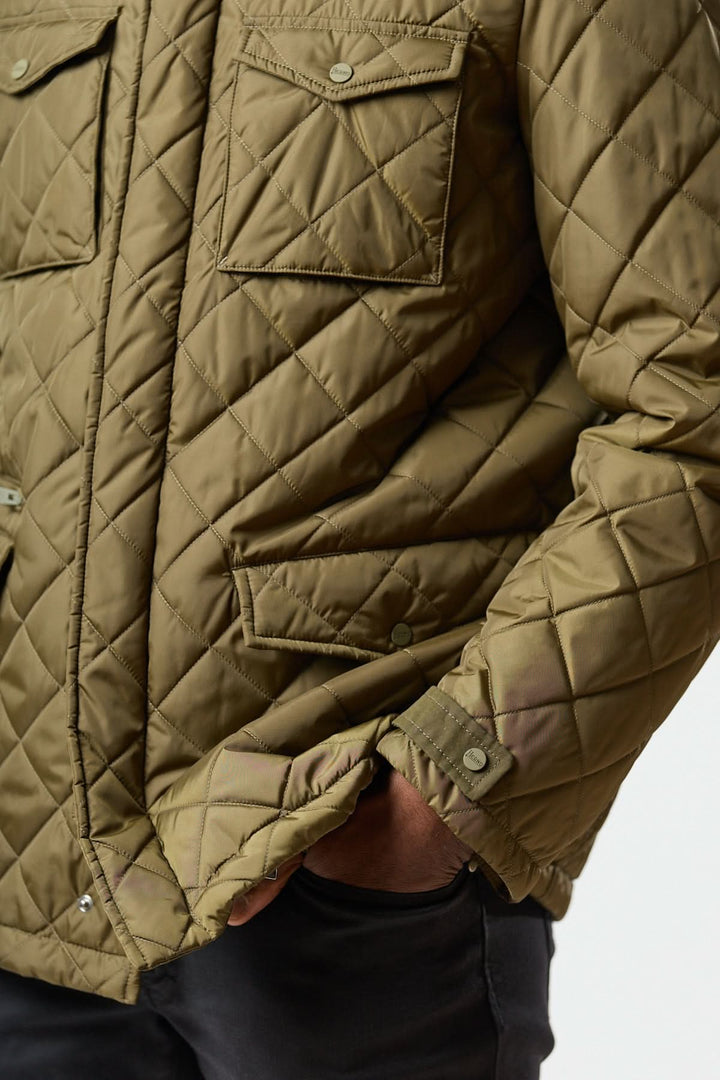Veste matelassée à capuche escamotable avec matelassage losange et poches pour un style utilitaire léger et chaud.