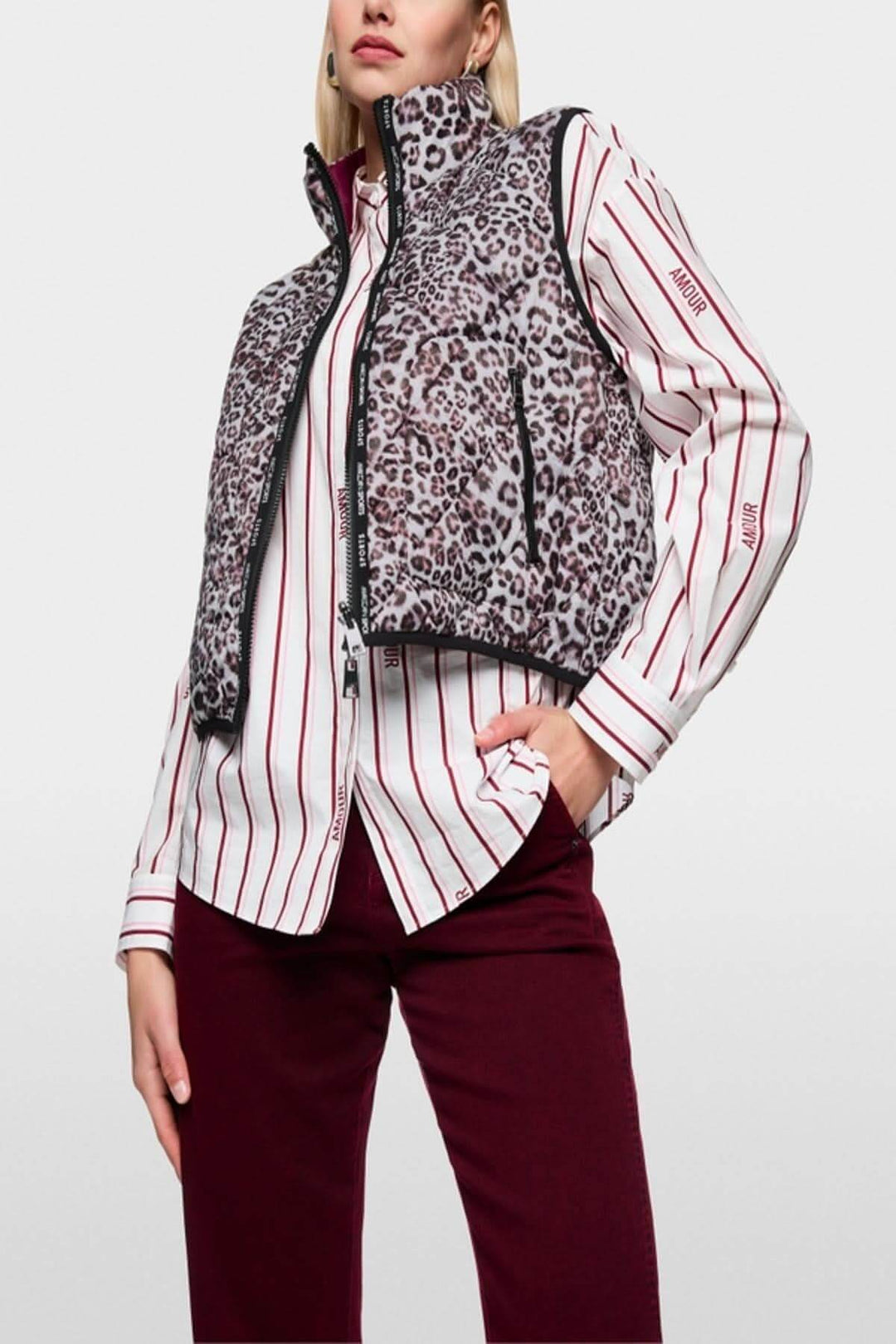 Veste sans manche réversible avec imprimé léopard, zippée, col montant et poches latérales, portée par un mannequin sur chemise rayée.