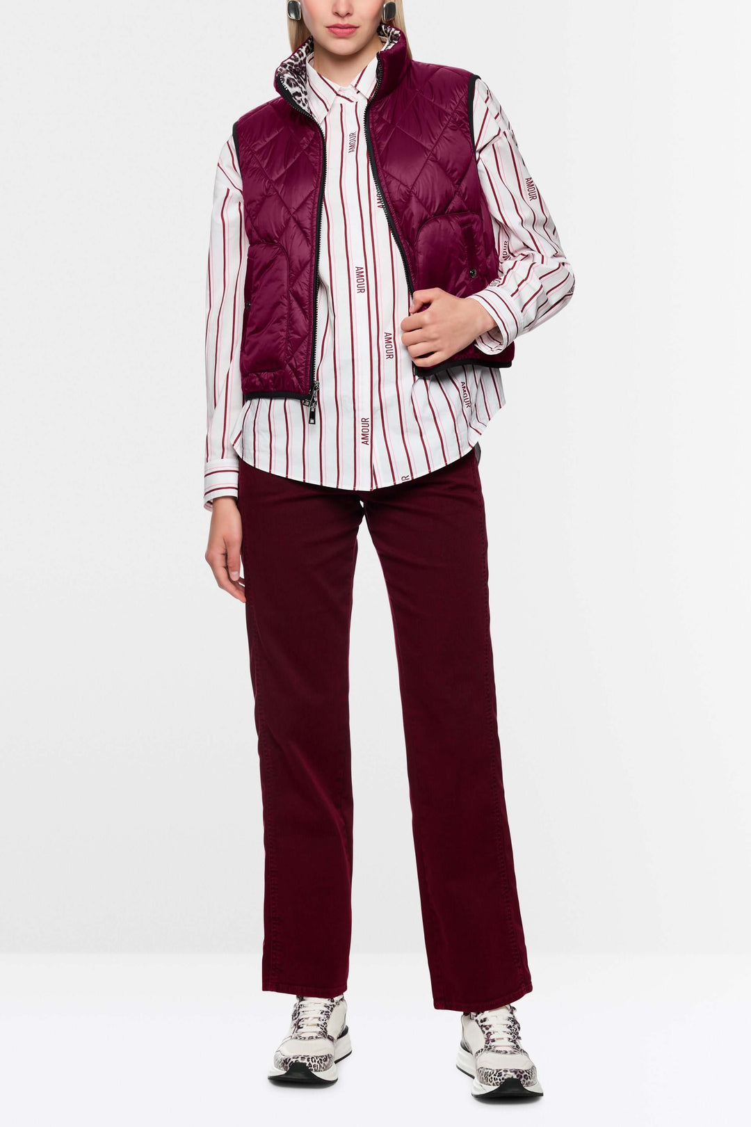 Femme portant une veste sans manche réversible bordeaux et chemise rayée.