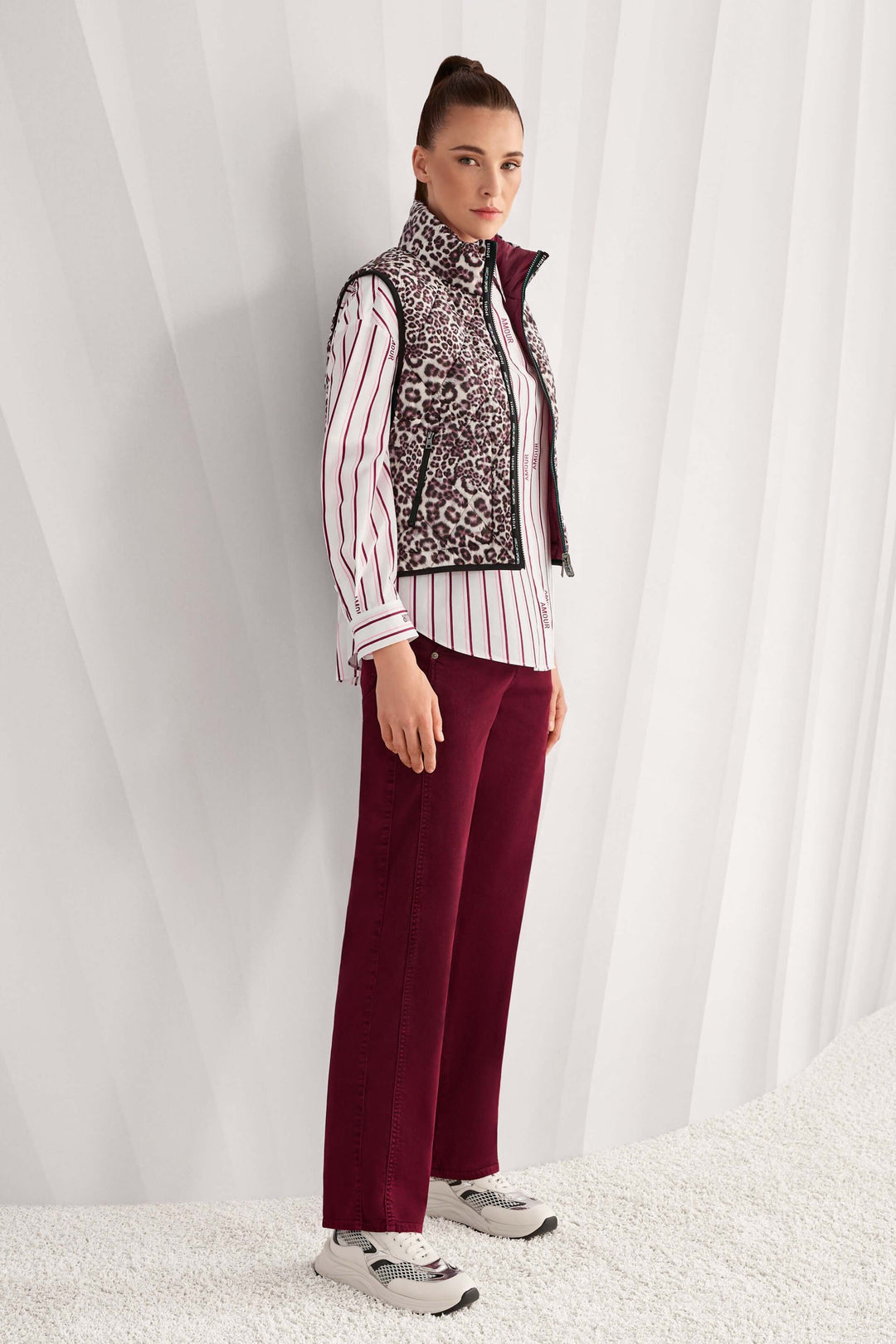 Femme portant une veste sans manche réversible avec imprimé léopard et col montant, combinant style classique et moderne.