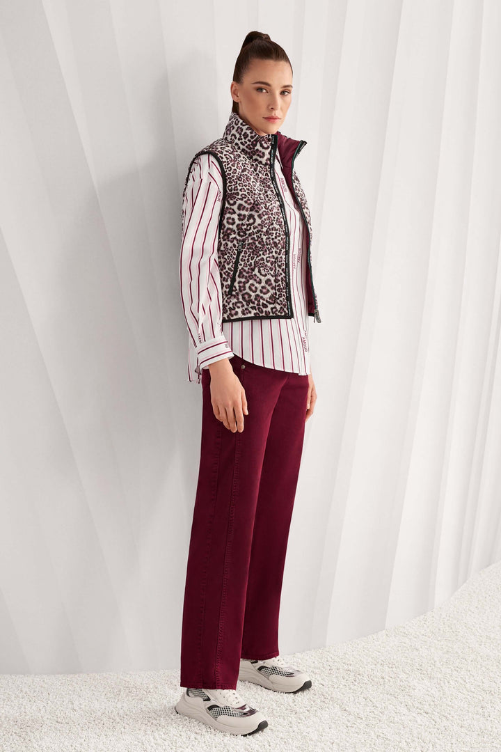 Femme portant une veste sans manche réversible avec imprimé léopard et col montant, combinant style classique et moderne.