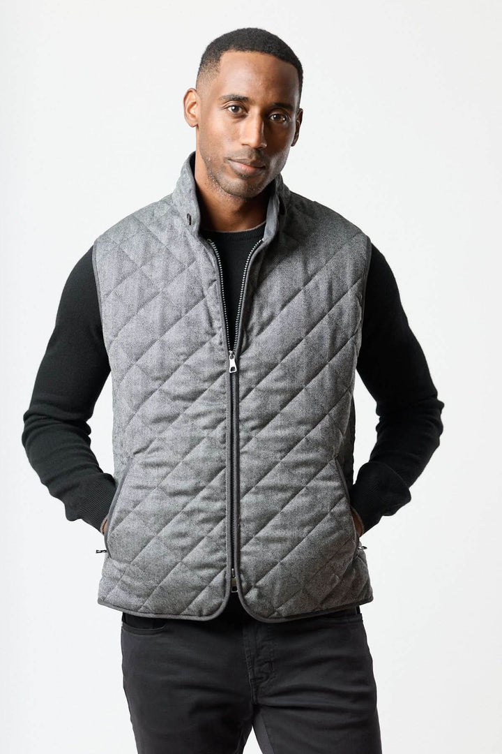 Homme portant une veste sans manches matelassée en laine à motif chevrons, élégante et ajustée avec col montant.