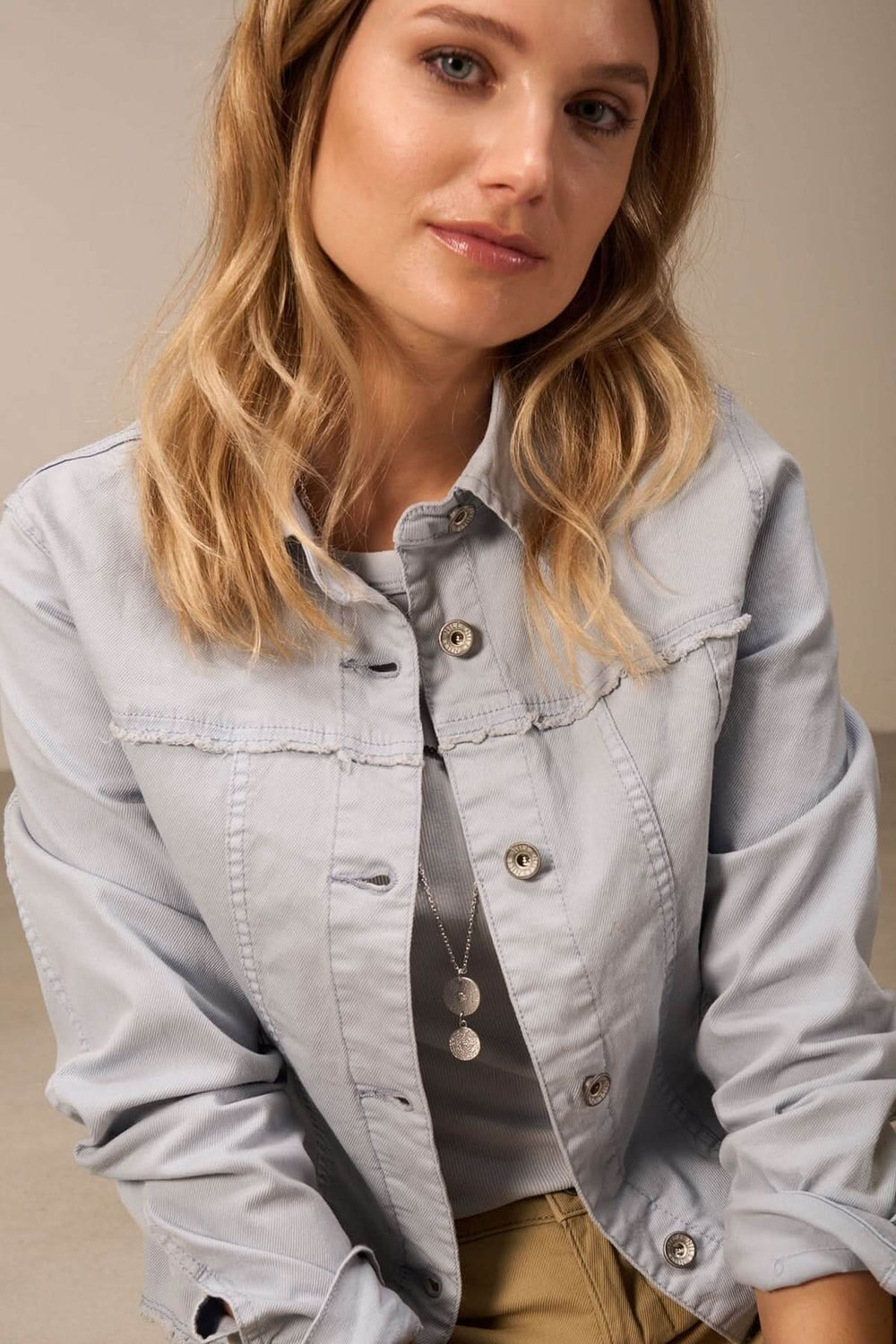 Femme portant une veste décontractée en denim bleu clair, avec un col et des boutons, style urbain.