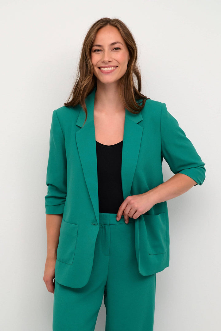 Veston Cocamia en vert avec manches retroussées, parfait pour femme professionnelle, style décontracté.