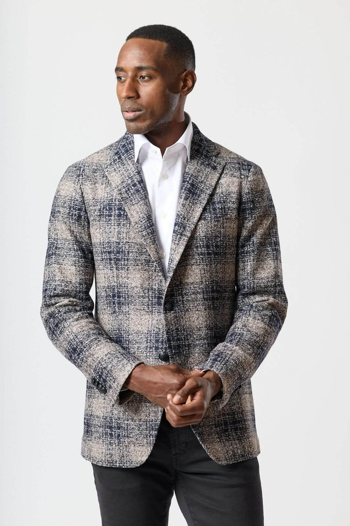 Homme portant un veston à carreaux brossé deux boutons avec une chemise blanche, style urbain élégant.