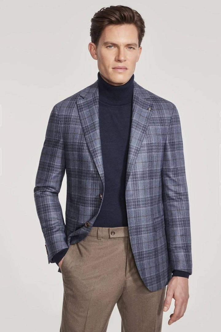Veston à carreaux en laine et soie porté par un homme, présenté avec un pull noir et un pantalon beige.