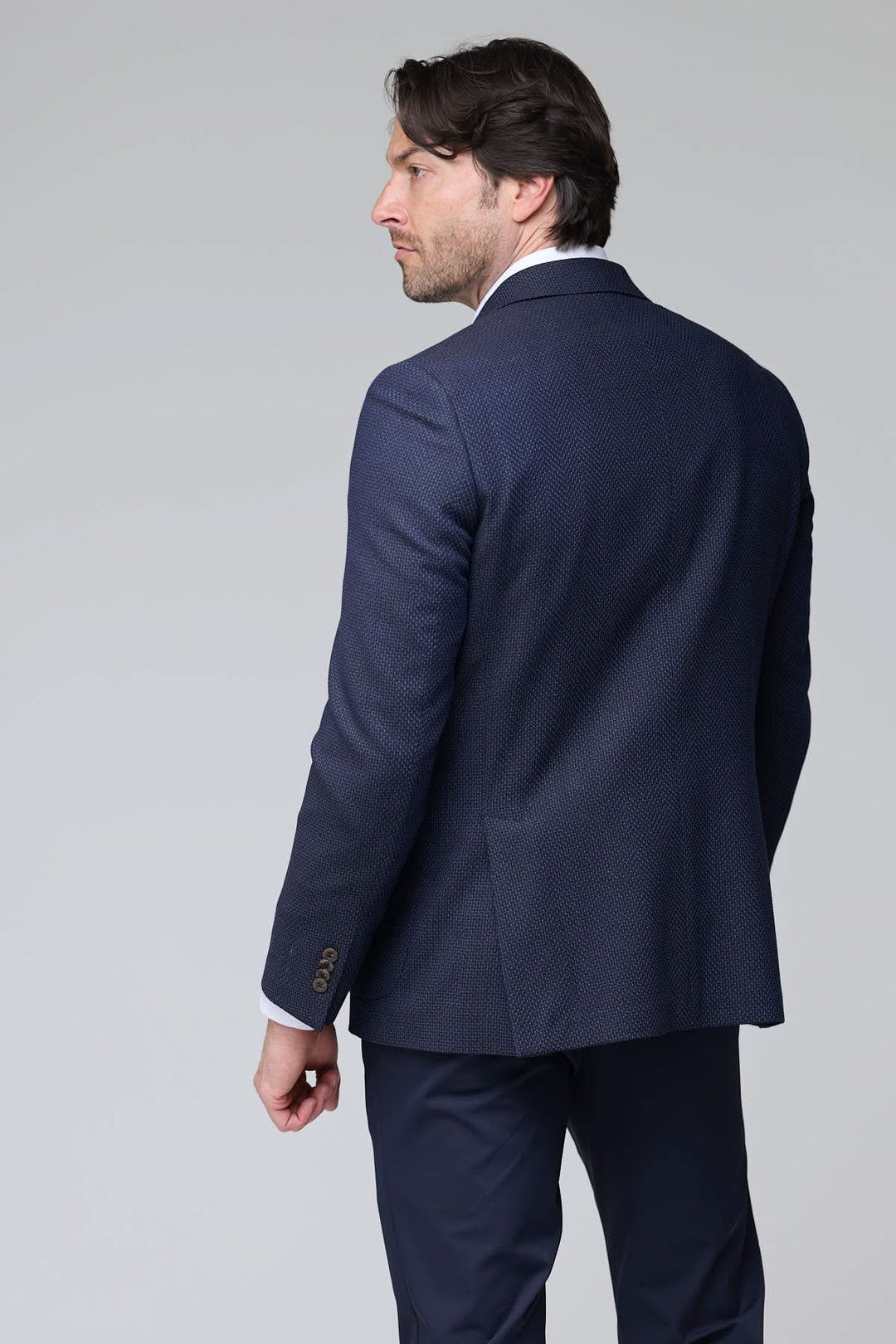 Homme portant un veston texturé à coupe moderne, dos, élégant et confortable pour le bureau et les sorties habillées. Décris moi le produit en français.