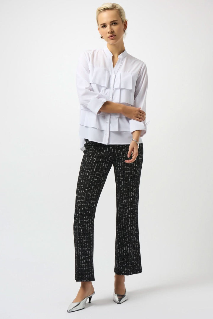 Pantalon évasé noir avec motif quadrillé blanc, porté avec chemisier blanc, pour un look chic et moderne.