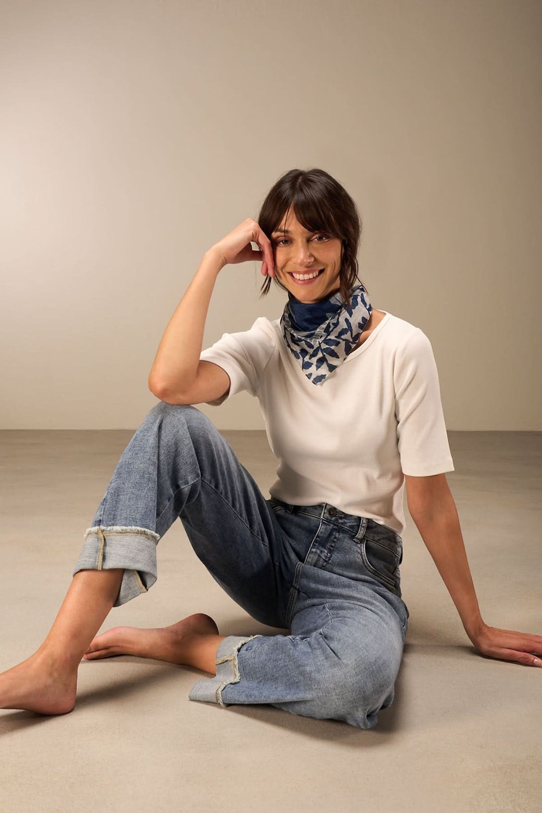 Foulard carré à imprimé feuillage porté avec un haut uni et un jean, ajoutant une touche élégante.
