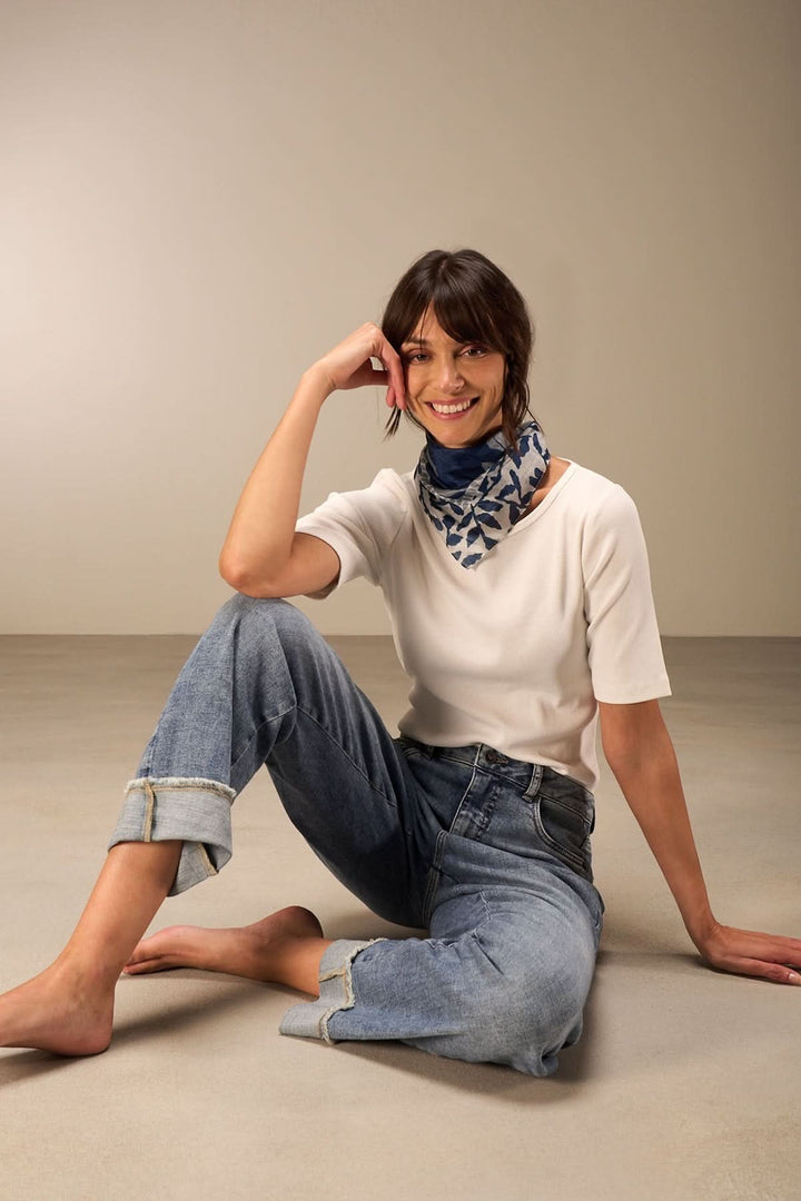 Foulard carré à imprimé feuillage porté avec un haut uni et un jean, ajoutant une touche élégante.