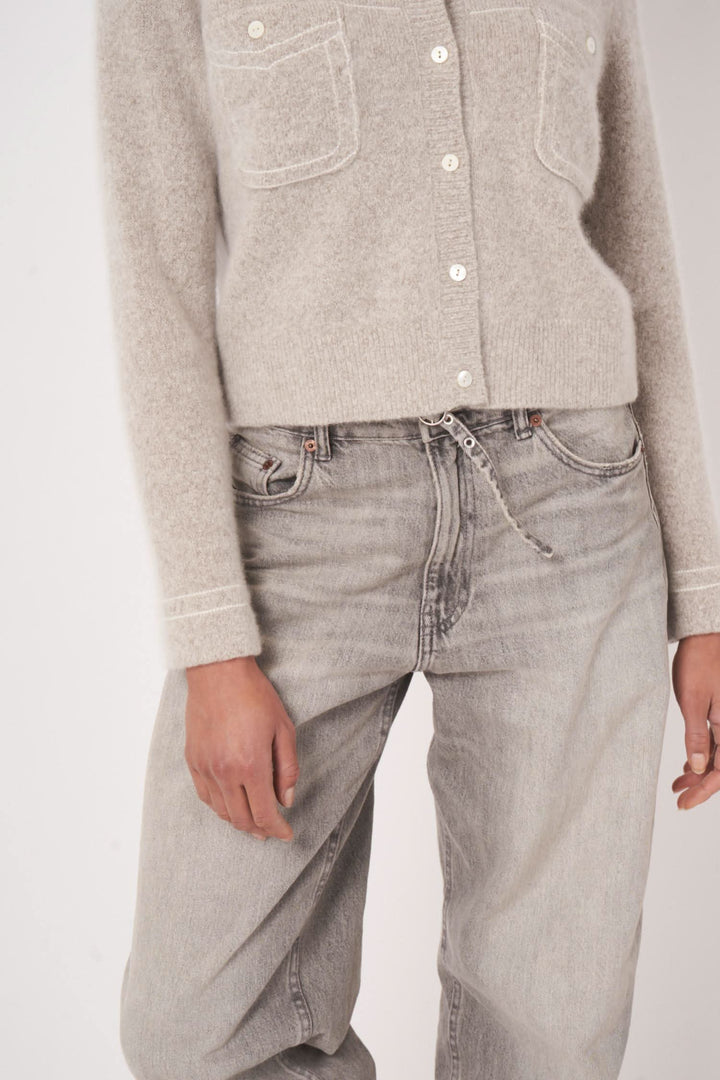 Cardigan en maille avec poches plaquées, porté avec un pantalon en denim gris, style décontracté pour l'automne.