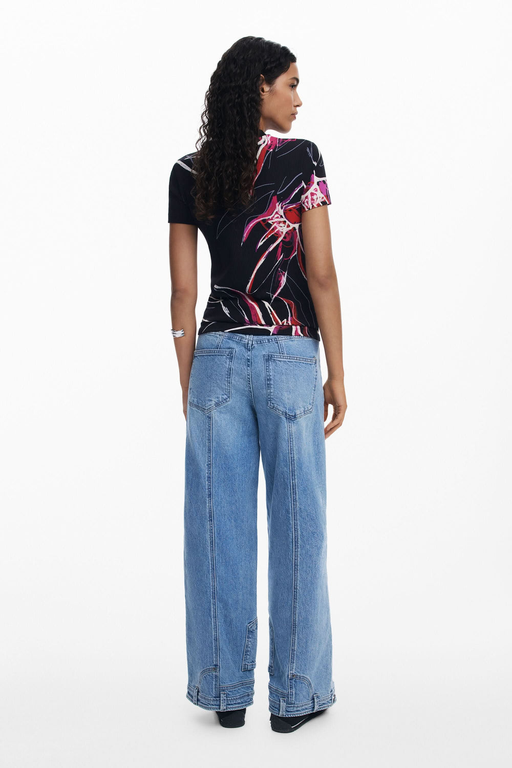 T-shirt noir à imprimé floral, porté avec un pantalon large, vue arrière, style moderne et confortable.