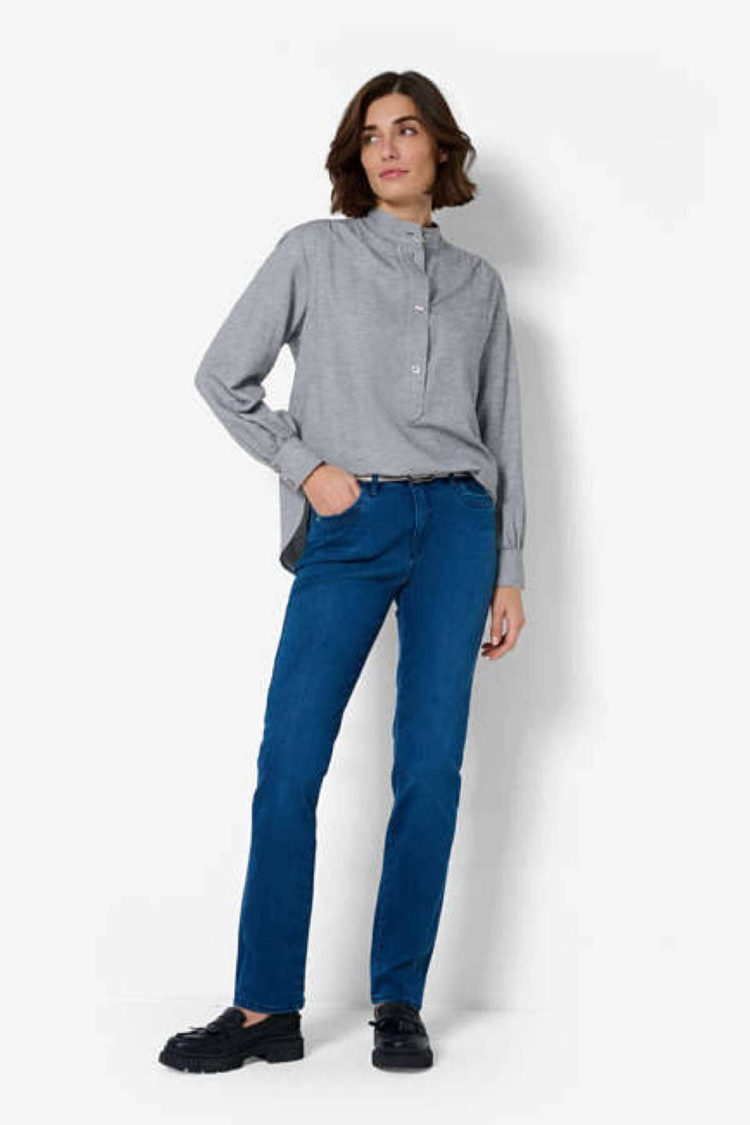 Femme portant un jean à cinq poches, coupe droite, avec une chemise grise, style décontracté.