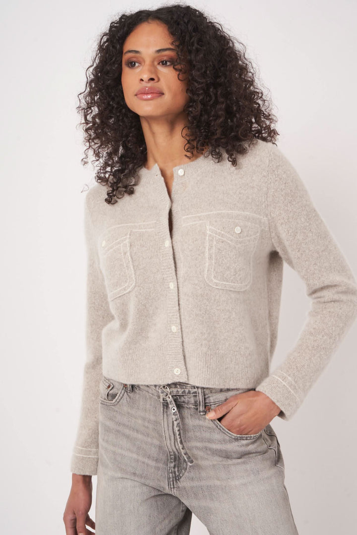 Cardigan en laine et cachemire beige avec poches plaquées, col rond et boutons, pour une allure élégante.
