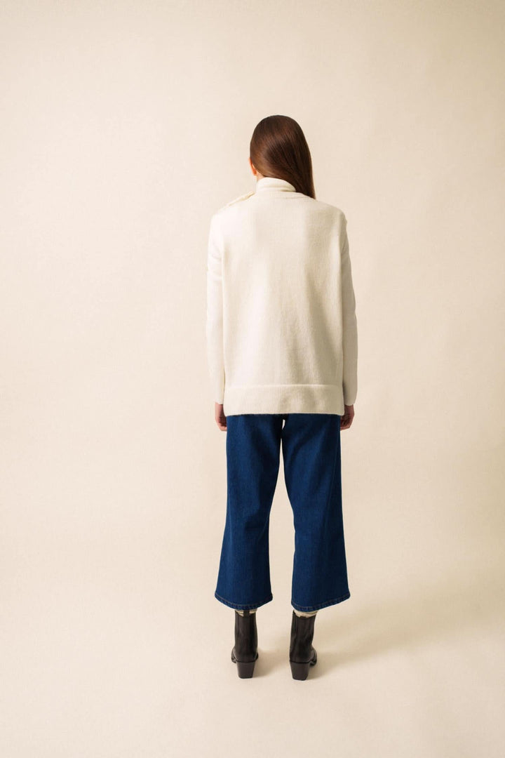 Veste sans manche blanche vue de dos, portée avec un pantalon bleu et des bottes noires.