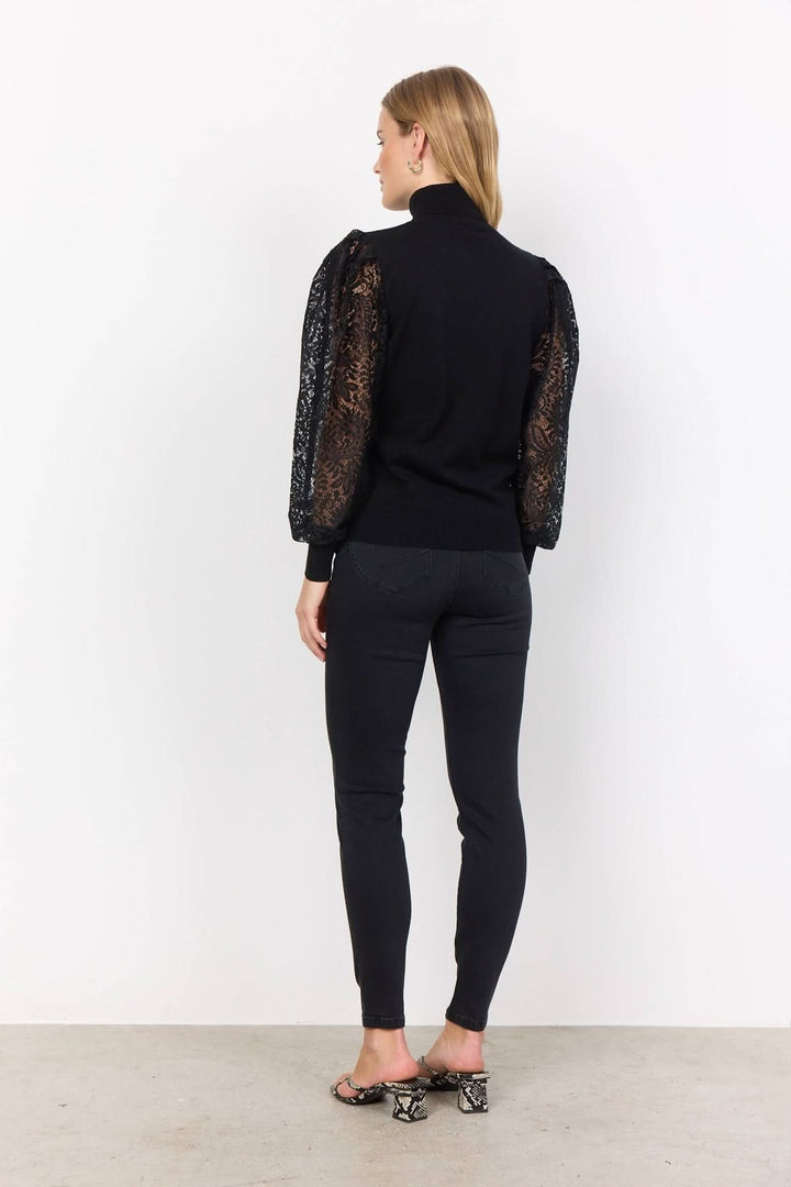 Chandail à col montant en noir avec manches en dentelle transparent, style chic et féminin.