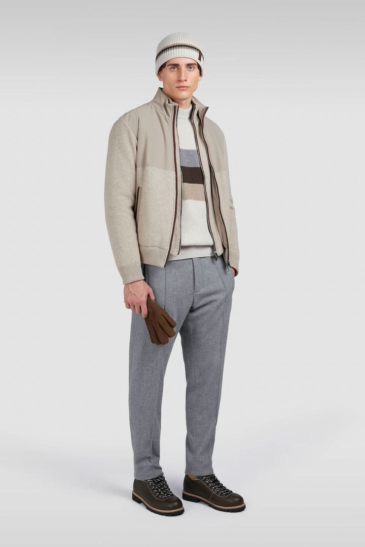Homme en tenue décontractée, portant une veste beige, pantalon gris, et accessoires assortis, style moderne.