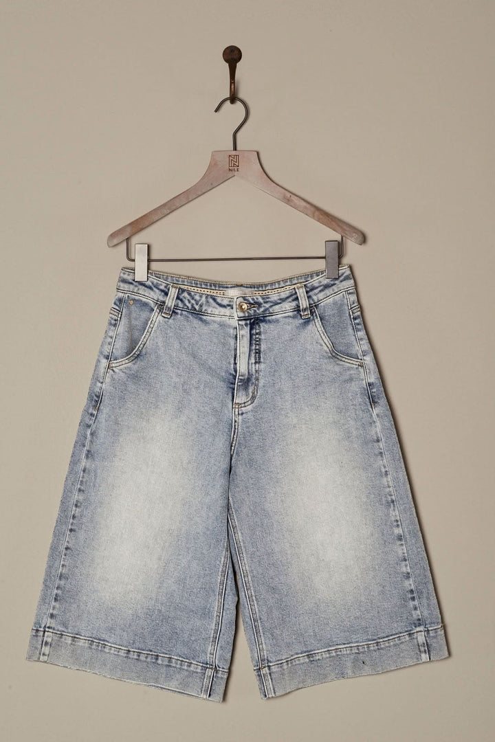 Bermuda en denim délavé, coupe ample, longueur genou, style décontracté, à accrocher sur un cintre.