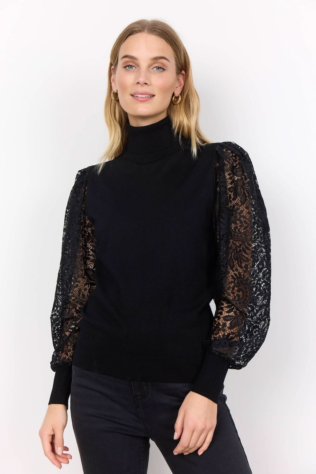 Chandail à col montant noir avec manches en dentelle transparente, look chic et féminin.