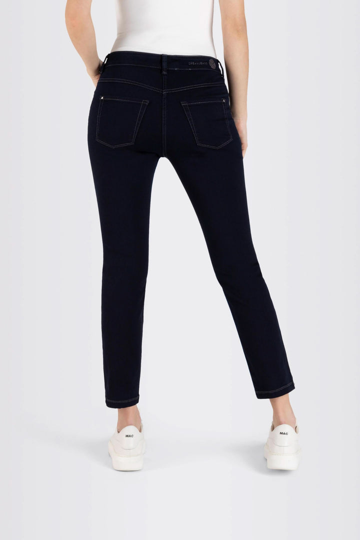 Femme portant des jeans coupe ajustée 7/8 avec surpiqûres contrastantes et sneakers blanches