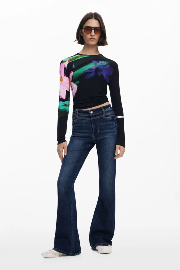 Femme portant un jean évasé taille haute avec un haut à motifs floraux et des lunettes de soleil.