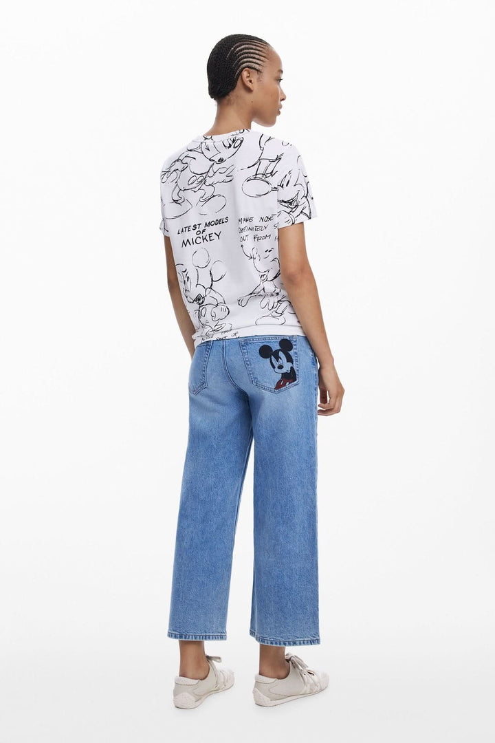 T-shirt Mickey à col rond avec motif artistique, associé à un jean bleu décontracté en look moderne.