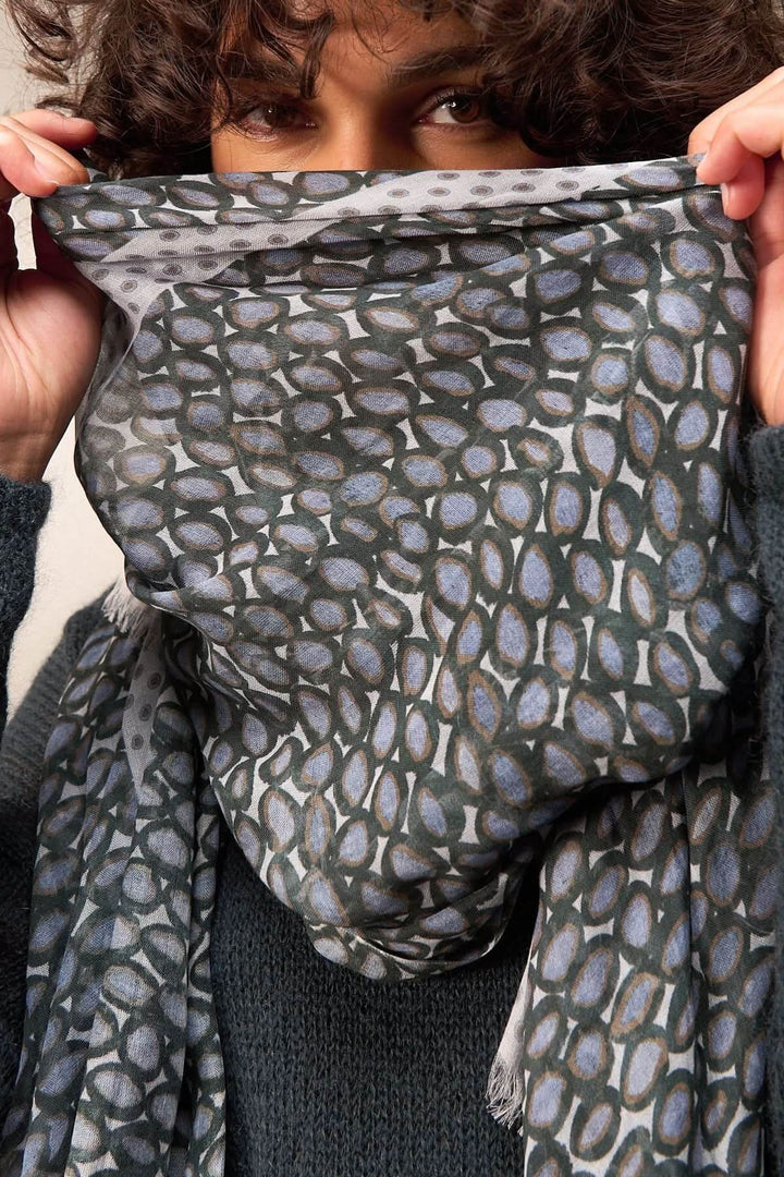 Foulard imprimé porté avec élégance, ajoutant une touche sophistiquée à une tenue, idéal pour un style moderne et raffiné.