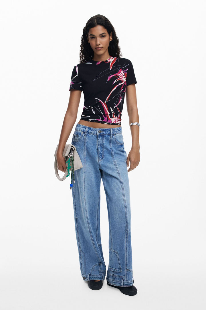 T-shirt imprimé floral noir ajusté avec jeans larges et sac à main, style tendance et moderne.