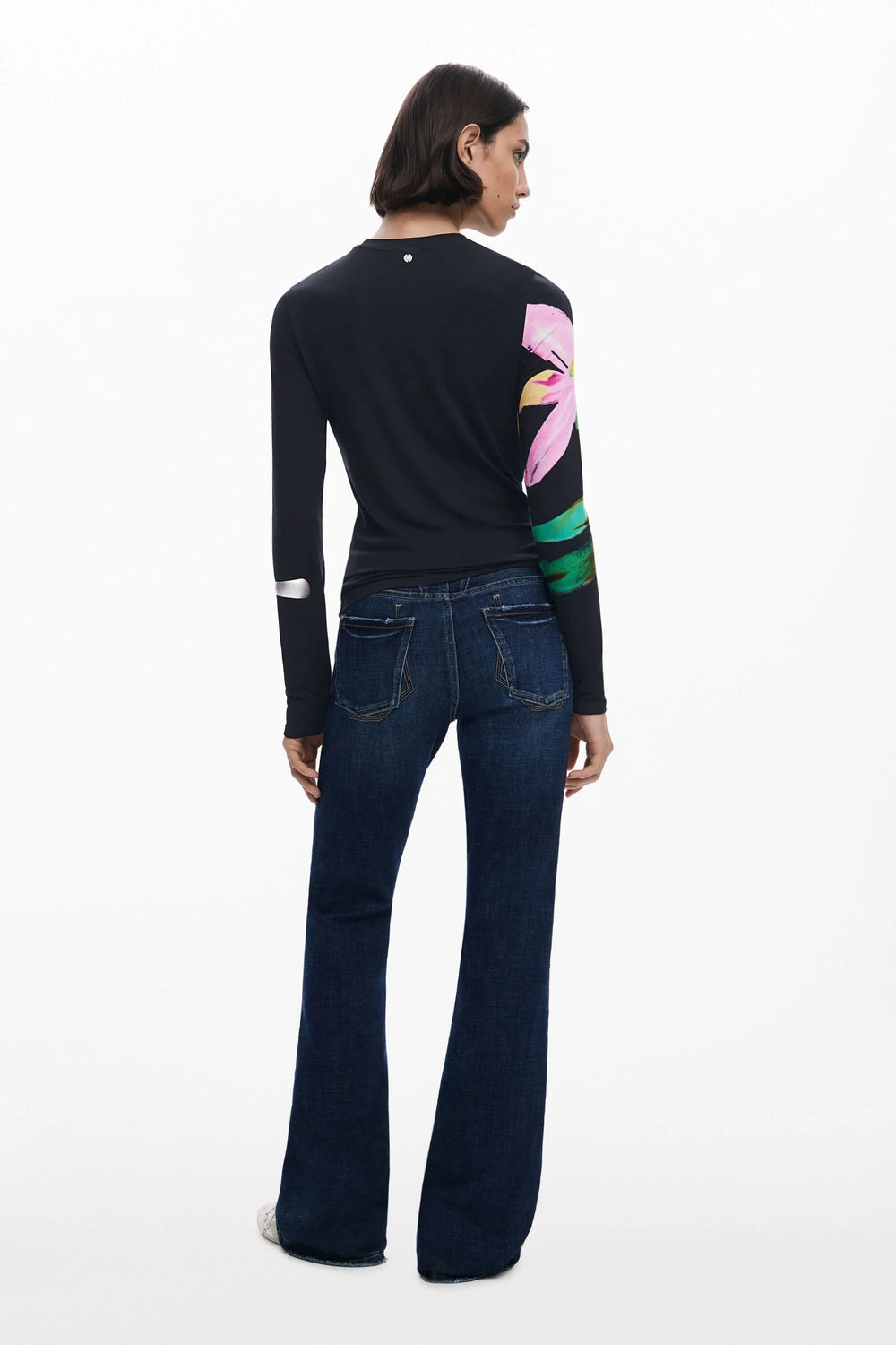T-shirt floral à manches longues sur fond sombre, porté avec un jean foncé, vue arrière.
