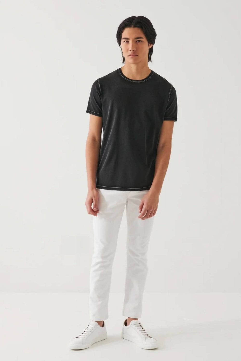 Homme portant un t-shirt noir près du corps avec un col ras du cou et un style décontracté.