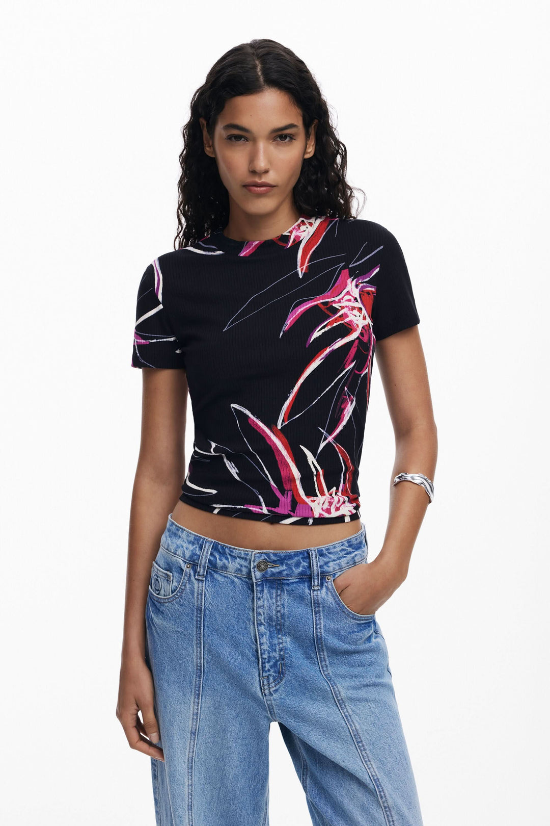 T-shirt à manches courtes avec imprimé floral graphique sur fond noir, porté avec un jean décontracté.