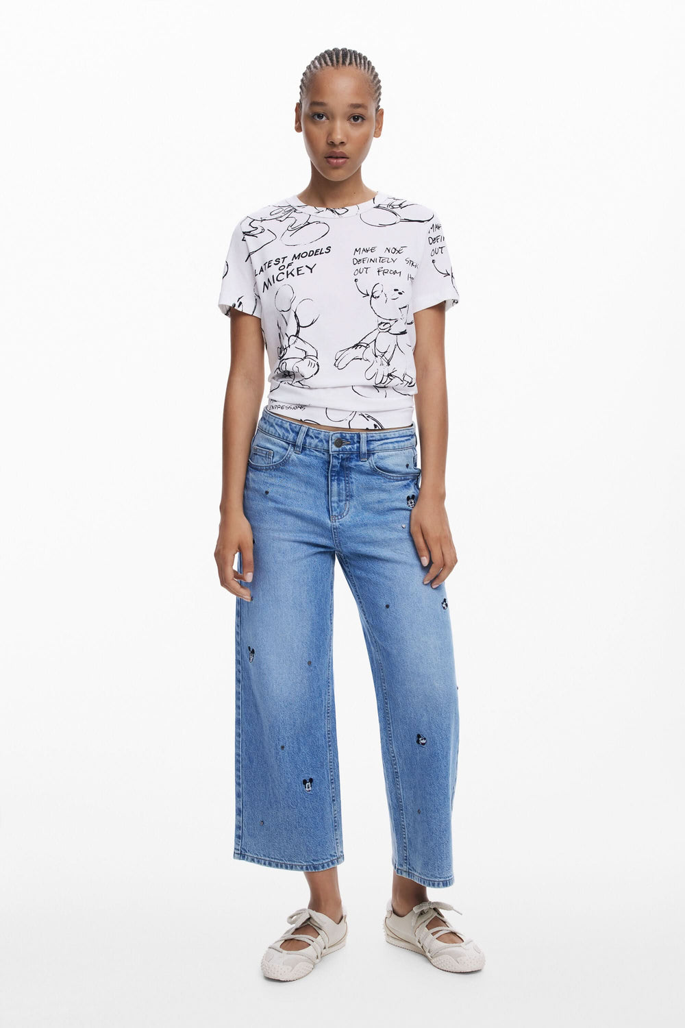 Femme portant un t-shirt Mickey artistique avec un jean décontracté, style urbain moderne.