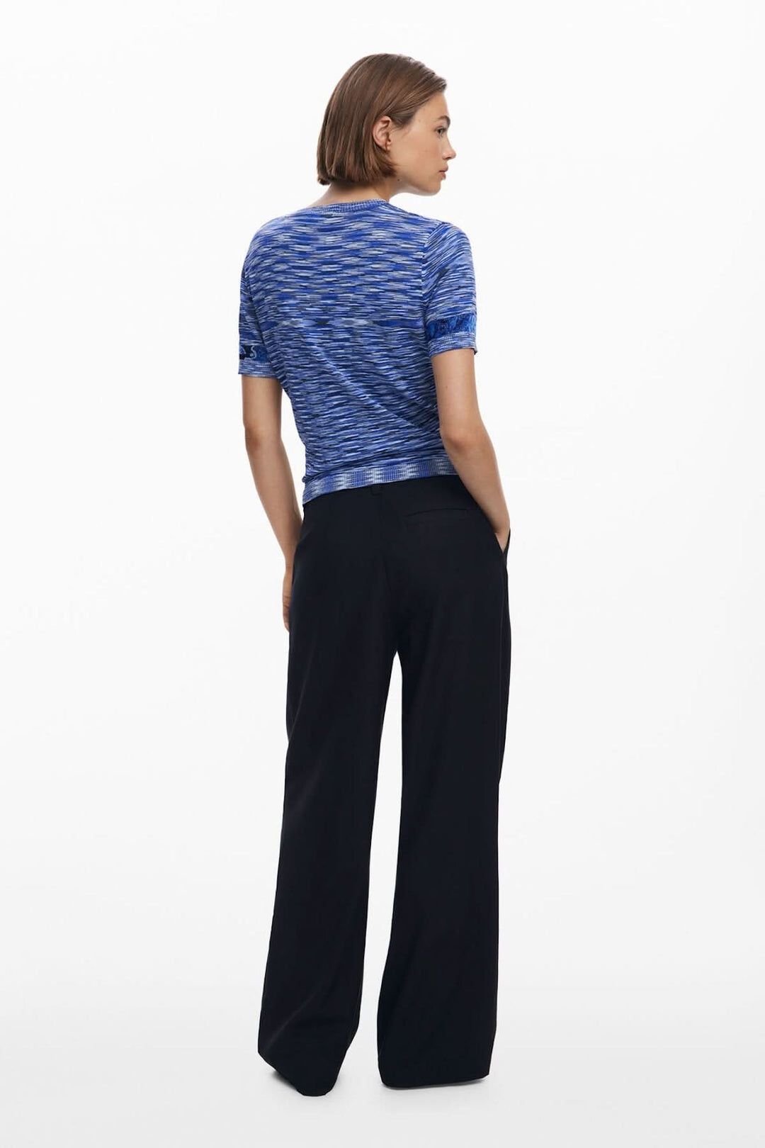 T-shirt en tricot à manches courtes, motif texturé bleu, porté avec un pantalon noir, vue de dos.