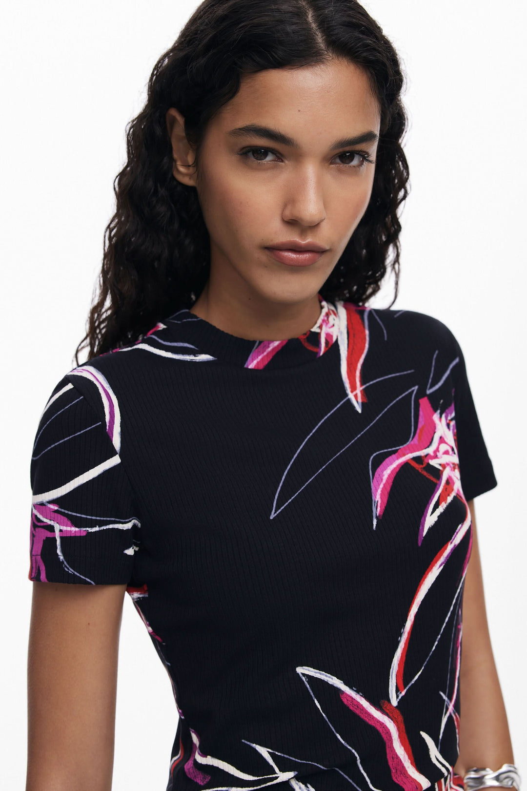 Femme portant un t-shirt à manches courtes avec imprimé floral vibrant sur fond noir.