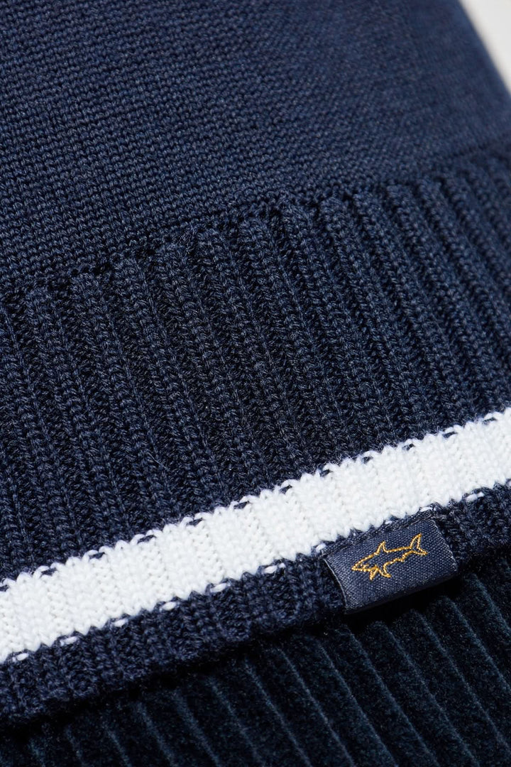 Chapeau en tricot bleu marine avec bande blanche et étiquette brodée, parfait pour les journées fraîches.