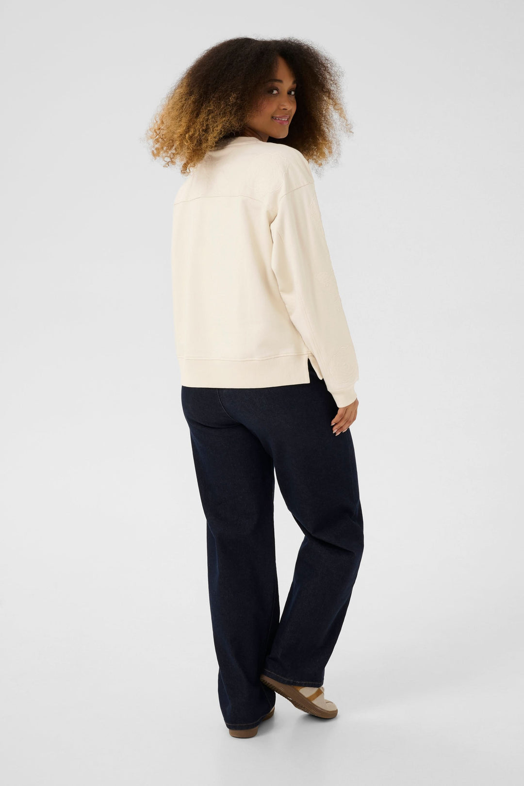 Femme portant un coton ouaté Josie crème, vue de dos avec un pantalon foncé, style décontracté et chic.