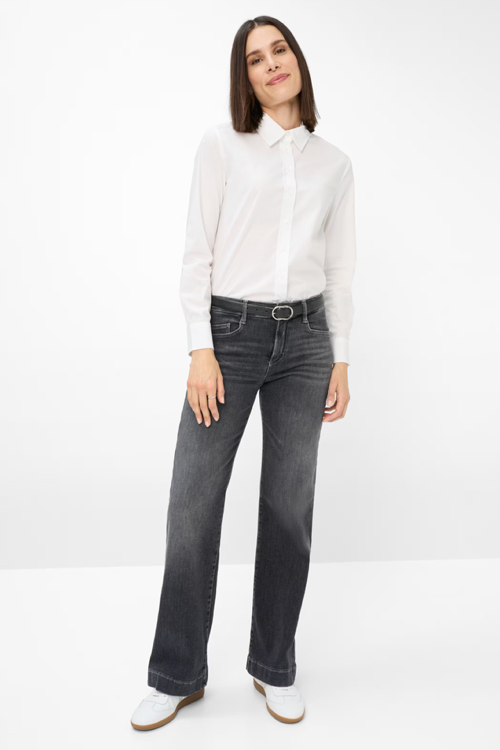 Jean délavé évasé porté avec une chemise blanche pour un look tendance et décontracté.