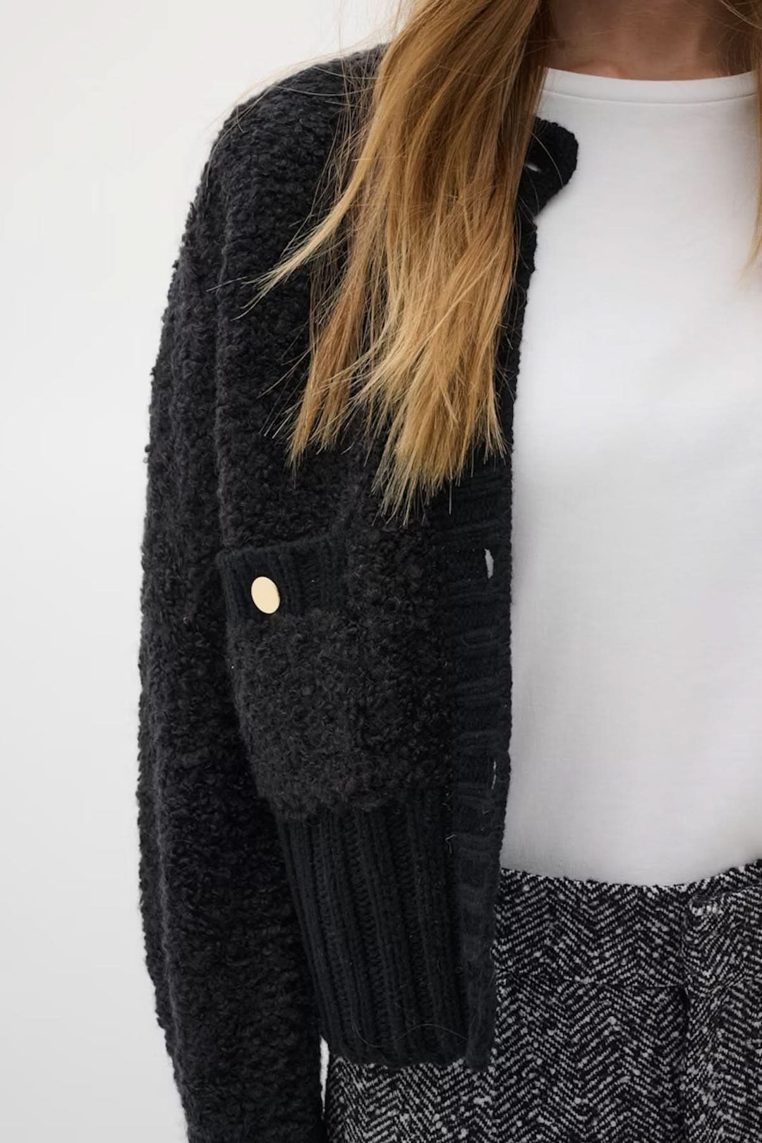 Femme portant le Cardigan Guo court structuré, maille texturée avec boutons dorés, style moderne et sophistiqué.