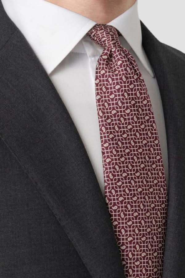 Homme en costume avec cravate à motif géométrique en soie italienne raffinée, élégante pour les occasions formelles et professionnelles.